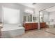 Bathroom featuring large mirrors, wooden cabinets, and a relaxing soaking tub at 1933 E Lafayette Ave, Gilbert, AZ 85298
