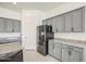 Elegant kitchen featuring gray cabinets, granite countertops, a stainless refrigerator, and tile flooring at 19742 W Harrison St, Buckeye, AZ 85326