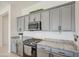 Close up of kitchen with stainless steel microwave and gas range with gray cabinets and granite countertops at 19742 W Harrison St, Buckeye, AZ 85326