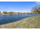 Peaceful lake view featuring blue water and manicured green space, showcasing a tranquil residential community amenity at 20181 N Lauren Rd, Maricopa, AZ 85138