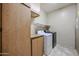 Well-equipped laundry room with washer, dryer, cabinets, and shelving for organized storage at 21549 N Backus Dr, Maricopa, AZ 85138