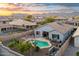 Aerial view of a fenced backyard with a pool, patio furniture, and mountain views at sunset at 21963 W Tonto St, Buckeye, AZ 85326