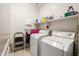 Well-lit laundry room with two washing machines, open shelf with laundry supplies, and drying rack at 21963 W Tonto St, Buckeye, AZ 85326