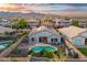Stunning aerial view of a home with a private pool, lush landscaping, and solar panels against a mountain backdrop at 21963 W Tonto St, Buckeye, AZ 85326
