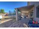 Covered patio with stone flooring, outdoor kitchen, and furniture, adjacent to the backyard at 22741 N Scott Dr, Maricopa, AZ 85138