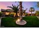 Lush backyard featuring vibrant green lawn, mature palm trees, and charming landscape lighting for evening enjoyment at 2361 N 156Th Dr, Goodyear, AZ 85395