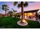 Beautiful backyard with mature palm trees, lawn, covered patio, and outdoor seating at 2361 N 156Th Dr, Goodyear, AZ 85395