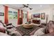 Comfortable living room with a sectional sofa, ceiling fans, and bright windows with orange curtains at 2361 N 156Th Dr, Goodyear, AZ 85395