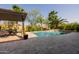 Backyard pool with travertine patio, a pergola, and lush landscaping provides the ideal space for outdoor enjoyment at 2361 N 156Th Dr, Goodyear, AZ 85395