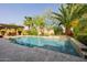 Backyard pool featuring travertine tile deck, lush tropical landscaping, and built-in waterfall feature for relaxation at 2361 N 156Th Dr, Goodyear, AZ 85395