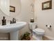 Compact powder room featuring a pedestal sink, toilet, and decorative accents at 2361 N 156Th Dr, Goodyear, AZ 85395