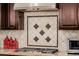 Close-up of modern stovetop with decorative backsplash, complementing the kitchen's design at 2361 N 156Th Dr, Goodyear, AZ 85395