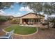 Beautiful landscaped backyard featuring turf, mature trees, and an extended covered patio with an outdoor jacuzzi at 27196 N 129Th Dr, Peoria, AZ 85383
