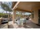 A cozy outdoor dining area is featured under the covered patio with a grill and lounge furniture at 27196 N 129Th Dr, Peoria, AZ 85383