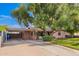 Wide view of the home featuring an extended driveway with a carport, mature trees, and a well-maintained lawn at 2942 E Mulberry Dr, Phoenix, AZ 85016