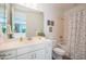 Bright, clean bathroom featuring a white vanity, floral shower curtain, and decorative wall art at 2973 E Austin Dr, Gilbert, AZ 85296