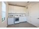 Bright laundry room with a window, gray tiled floors, washer, dryer and white cabinets at 2973 E Austin Dr, Gilbert, AZ 85296
