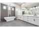 Modern bathroom featuring a freestanding tub, dual vanities, and sleek, gray tile flooring at 3046 W Redwood Ln, Phoenix, AZ 85045