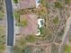 Overhead view of a house with a pool, putting green, and lush landscaping. Desert terrain in background at 33242 N 68Th Pl, Scottsdale, AZ 85266