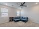 Bright living room with a blue sectional sofa, ceiling fan, neutral carpet, and natural light at 37185 N Falabella Dr, San Tan Valley, AZ 85140
