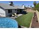 Large backyard with artificial turf, a pool, and a covered patio for entertaining at 4038 W Windrose Dr, Phoenix, AZ 85029
