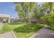 Landscaped backyard featuring a lush green lawn, mature trees, a playground, and a covered patio area at 4215 S Marisol Ln, Gilbert, AZ 85297
