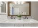 Bathroom featuring double sinks, a marble countertop, and a large mirror with a wooden frame at 4215 S Marisol Ln, Gilbert, AZ 85297