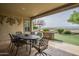 Relaxing covered patio featuring an outdoor dining set and a view of the landscaped backyard at 4497 E Ficus Way, Gilbert, AZ 85298
