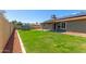 View of the backyard with green grass, patio, and partial solar panels at 6413 W Monte Cristo Ave, Glendale, AZ 85306