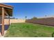View of the backyard with green grass, brick wall, and palm trees in distance at 6413 W Monte Cristo Ave, Glendale, AZ 85306
