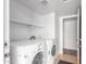 Well-lit laundry room with white washer and dryer, storage shelves and door at 6413 W Monte Cristo Ave, Glendale, AZ 85306