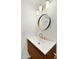 Modern bathroom vanity with a wood accent base, gold faucet, and a stylish, round mirror at 6833 E Grandview Dr, Scottsdale, AZ 85254