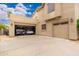 Exterior angle of a home featuring an attached three car garage, light fixtures, and desert landscaping at 1074 E Carla Vista Ct, Gilbert, AZ 85295