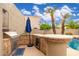 Outdoor kitchen features a built-in grill, refrigerator, and bar area overlooking the pool at 1074 E Carla Vista Ct, Gilbert, AZ 85295