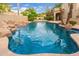 Backyard features a stunning pool with rock accents, lush landscaping, and a covered patio at 1074 E Carla Vista Ct, Gilbert, AZ 85295