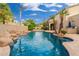 Beautiful pool area with a rock waterfall, mature palm trees, and a covered patio for entertaining at 1074 E Carla Vista Ct, Gilbert, AZ 85295