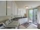 Modern laundry room featuring sleek white cabinetry, sink, and a view of the patio at 11736 E Del Timbre Dr, Scottsdale, AZ 85259