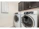 Bright laundry room with two front-load washers, dark cabinets, and light walls at 12031 S 184Th Ave, Goodyear, AZ 85338