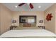 Well-lit bedroom with a large mirror, a ceiling fan, and a red flower decoration on the wall at 14239 W Port Royale Ln, Surprise, AZ 85379