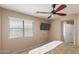 Bright bedroom with a ceiling fan, a window with blinds, and a wall-mounted TV at 14239 W Port Royale Ln, Surprise, AZ 85379