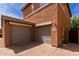Exterior view of two-story home with a two-car garage and a brick driveway at 14239 W Port Royale Ln, Surprise, AZ 85379