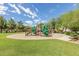 Community playground with green and red playset, sand base and lush green grass at 14239 W Port Royale Ln, Surprise, AZ 85379