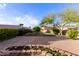 A spacious backyard featuring a large brick patio, lush green grass, mature trees, and a charming flower bed at 14722 W Lucas Ln, Surprise, AZ 85374