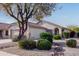 Charming single-story home featuring tan facade, desert landscaping, and a mature tree in the front yard at 14722 W Lucas Ln, Surprise, AZ 85374