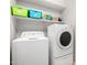 Functional laundry room with white washer and dryer, storage shelves, and bright lighting at 15328 W Memory Ln, Surprise, AZ 85374