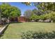 Wide-open backyard featuring a wooden fence, established landscaping, and mature shade trees at 16322 E Fairview St, Gilbert, AZ 85295