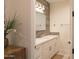 Bright bathroom featuring a white vanity with quartz countertop, modern fixtures, and wood-look tiling around the mirror at 16322 E Fairview St, Gilbert, AZ 85295