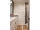 Bright bathroom featuring a white vanity, quartz countertop, and a sleek, glass-enclosed shower with wood-look tiling at 16322 E Fairview St, Gilbert, AZ 85295