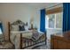 Cozy bedroom with a decorative metal bed frame, a window with blue curtains, and stylish patterned rug at 16322 E Fairview St, Gilbert, AZ 85295