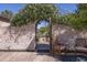 Charming wooden garden door in a brick wall, framed by white flowers and leading to a wooden bridge at 16322 E Fairview St, Gilbert, AZ 85295